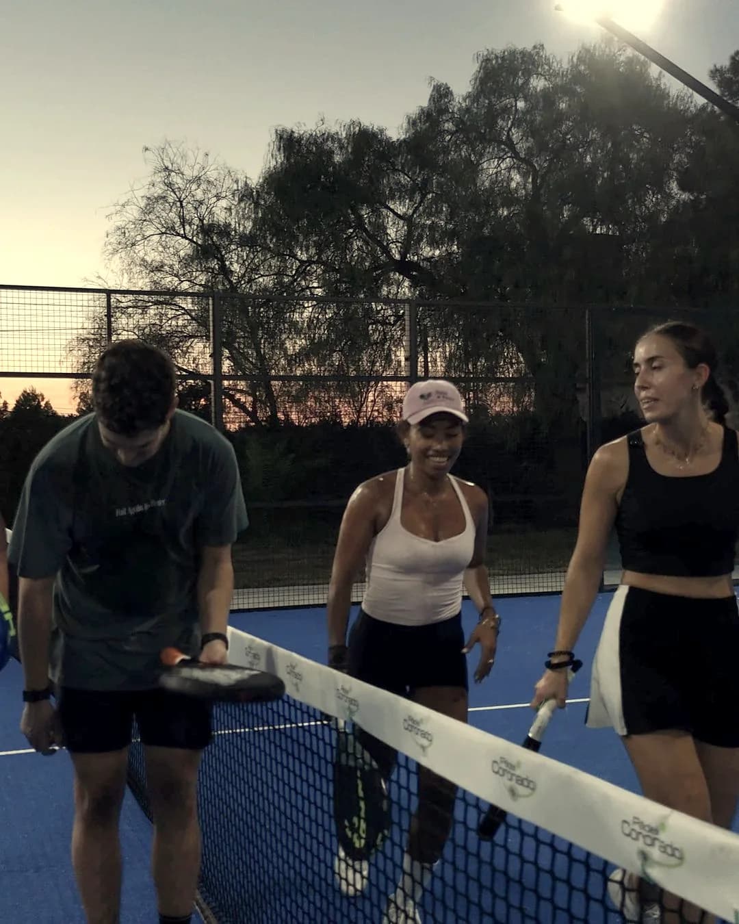 Four players laughing by the net at sunset