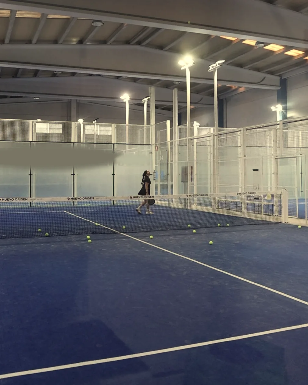 La nave cubierta de Origen Padel Club: el techo, los focos y una pista azul con la red