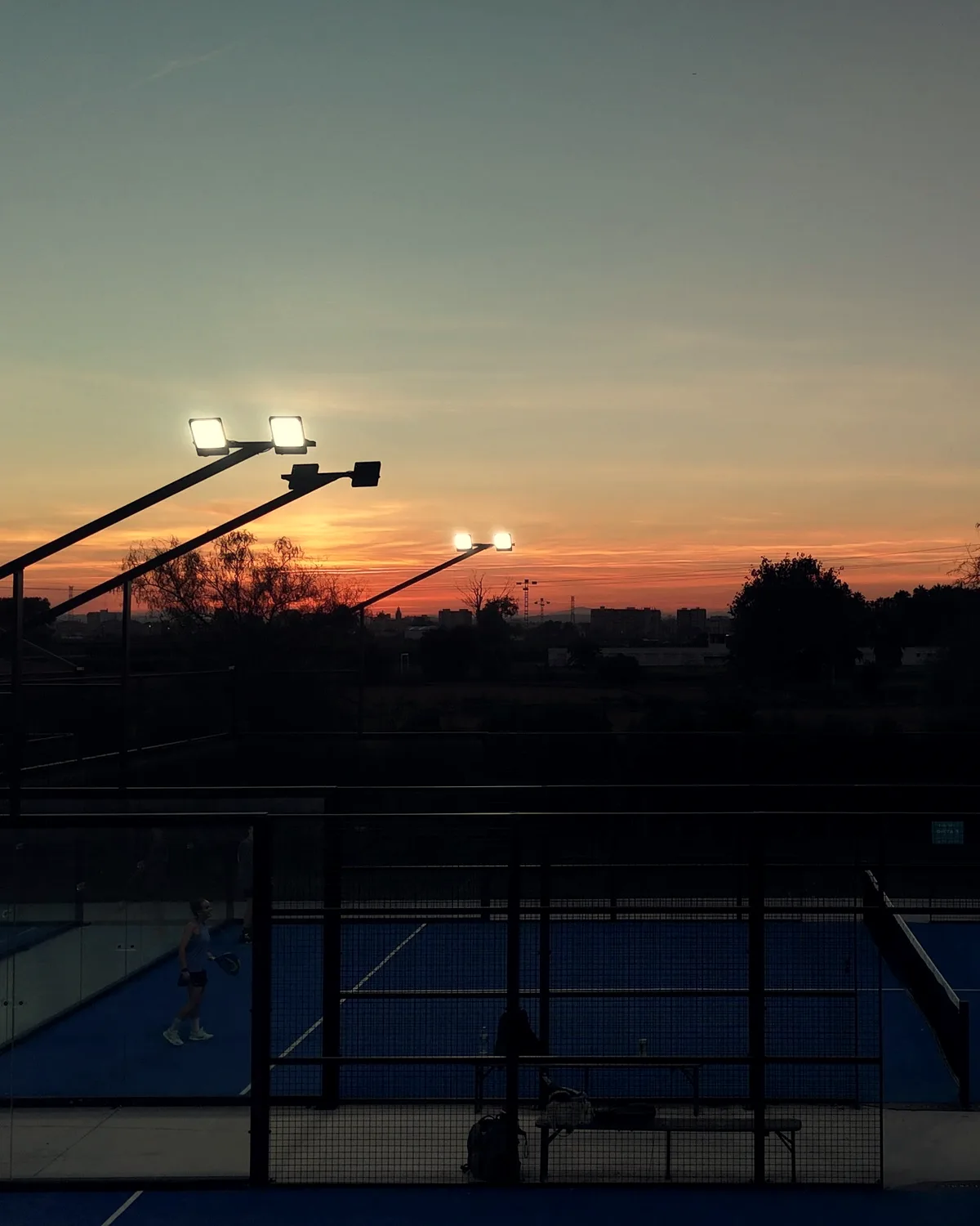 Pistas de pádel al atardecer con los focos encendidos, vistas desde un dron