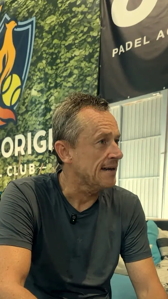 Un jugador habla sentado delante de las lonas del club y de JA Padel Academy.