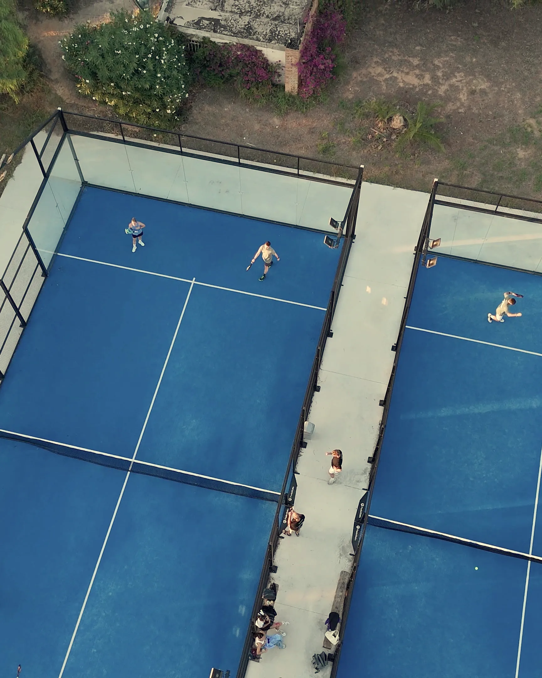 Dos pistas del Club Deportivo Saladar vistas desde un dron, con el pasillo entre ellas y los árboles alrededor